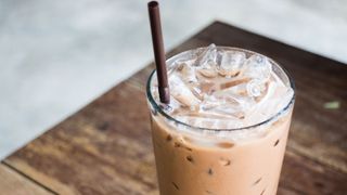 Ice coffee in a glass, sitting on table with straw