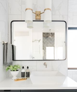 Gray bathroom cabinet with white basin, wall mirror and white sconce lighting