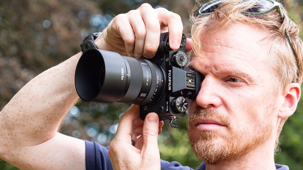 Viltrox AF 90mm f/2.2 EVO lens attached to a Fujifilm X-T5 camera, held by tech journalist and pro photographer Tim Coleman