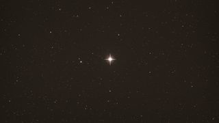 An image of the night sky with one very bright star in the middle