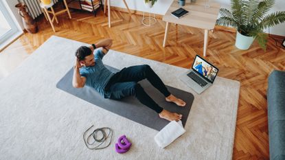 Man performing a crunch at home on a yoga mat