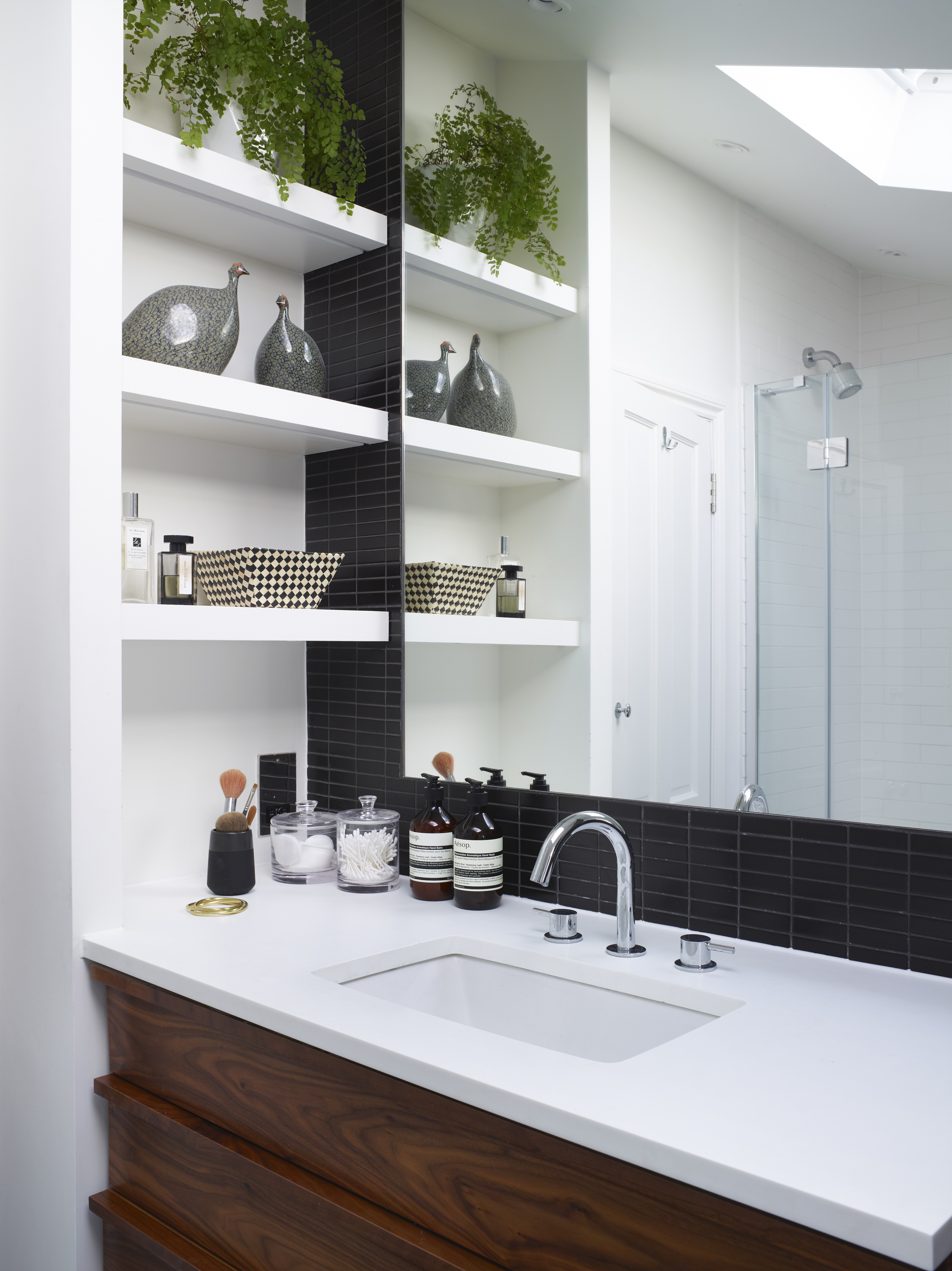 Comptoir de salle de bain blanc avec vasque encastrée, miroir au-dessus et étagères sur un côté