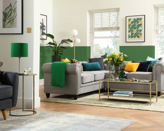 living room with a grey L shaped sofa, green and white walls and a rug