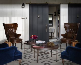 A lounge area with high back chairs and blue velvet armchairs