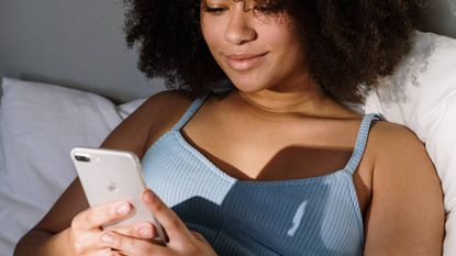 Woman using her iPhone while in bed