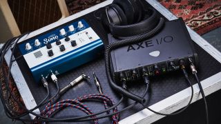 IK Multimedia Axe I/O and Audient Sono on a flight case surrounded by guitar cables and headphones 