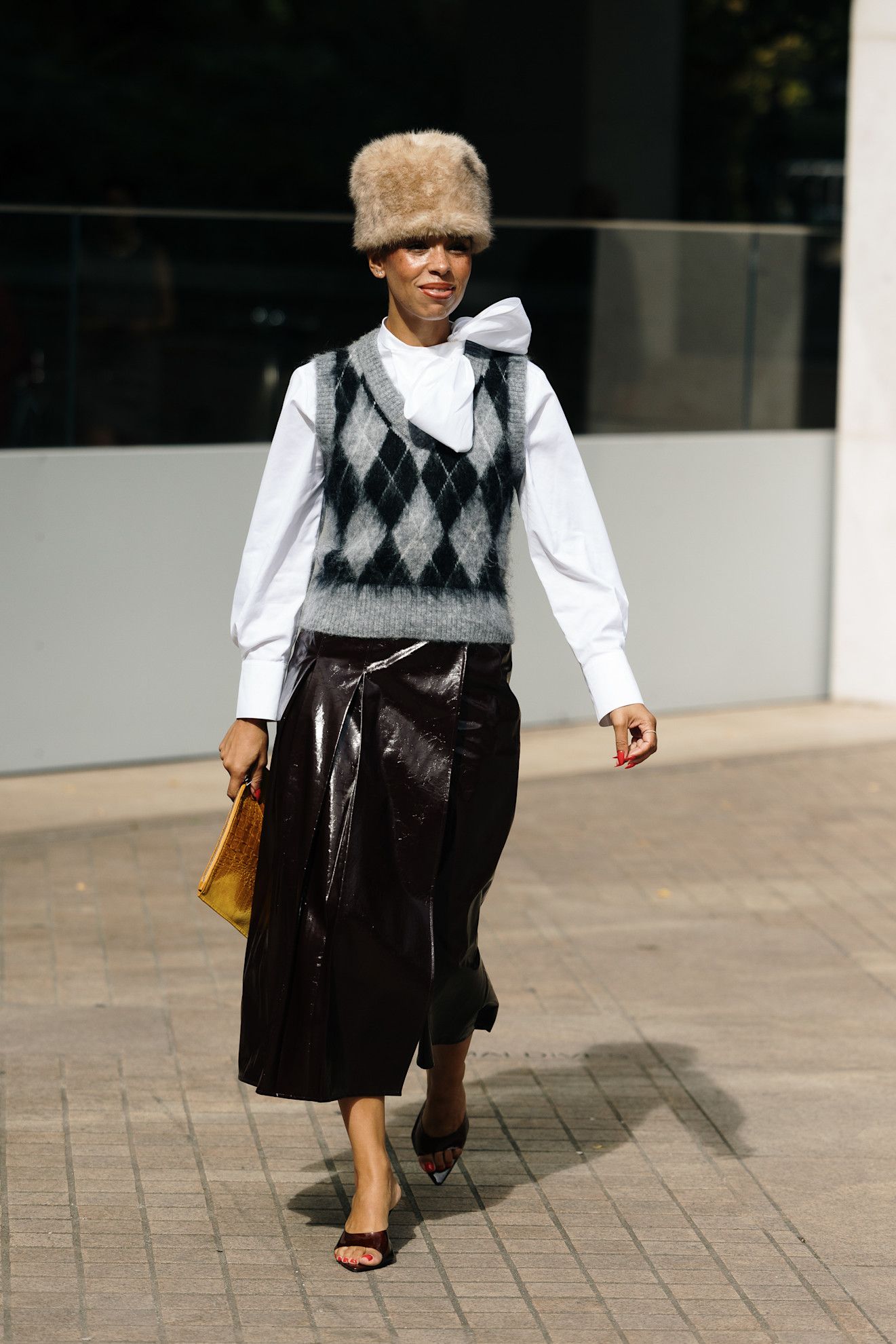 woman wearing sweater vest, skirt, fur hat, and heels