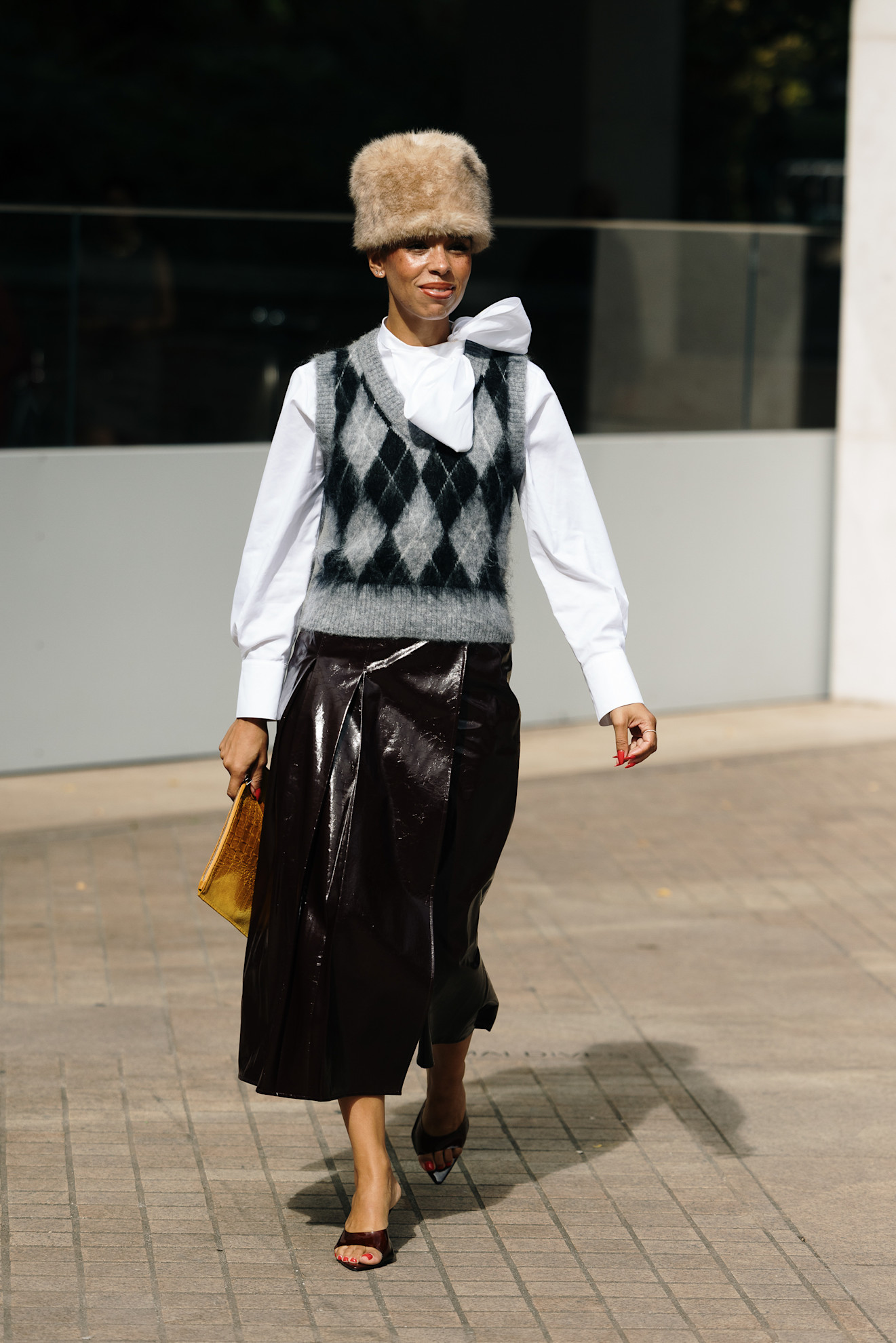 woman wearing sweater vest, skirt, fur hat, and heels