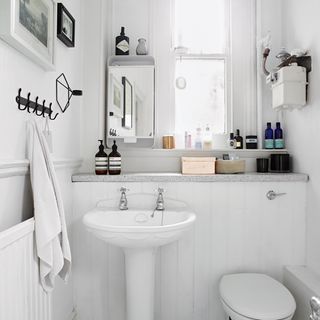 bathroom with white wall and wash basin with towel on hook