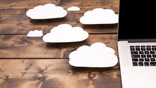 A laptop on a table surrounded by small clouds