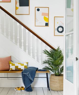 hallway with stairs white walls and bench