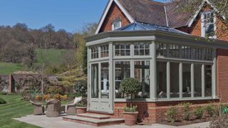 sage green conservatory on traditional brick house