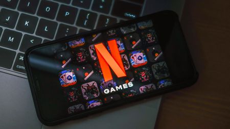 Netflix Games home screen on a phone, above a laptop