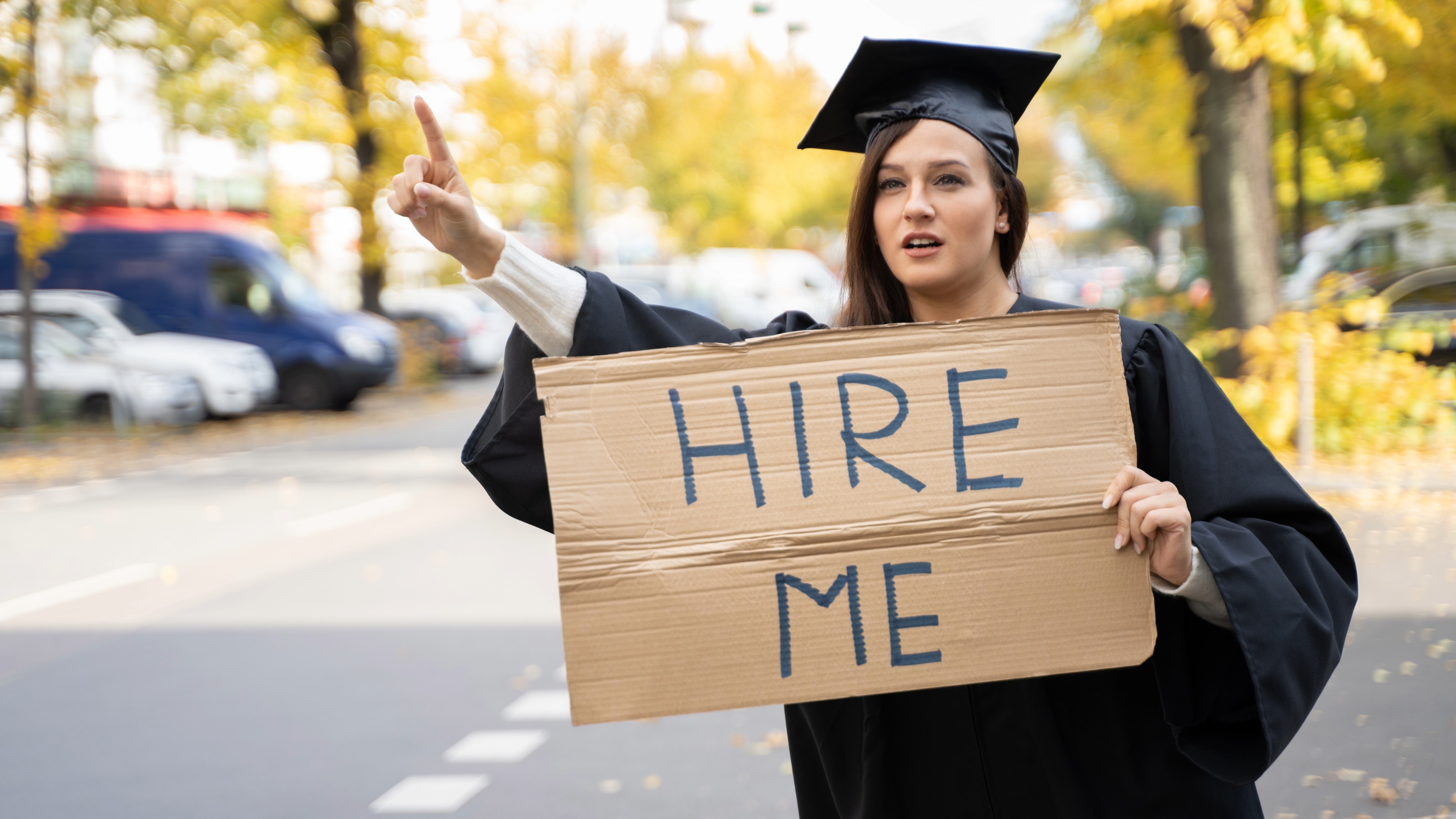 Graduate Student Standing With Hire Me Placard On Street
