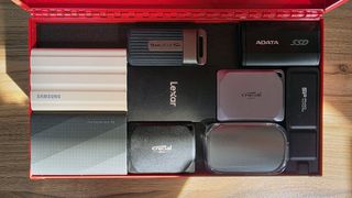 A collection of the best SSDs we've tested, in a small red toolbox, on a wooden table
