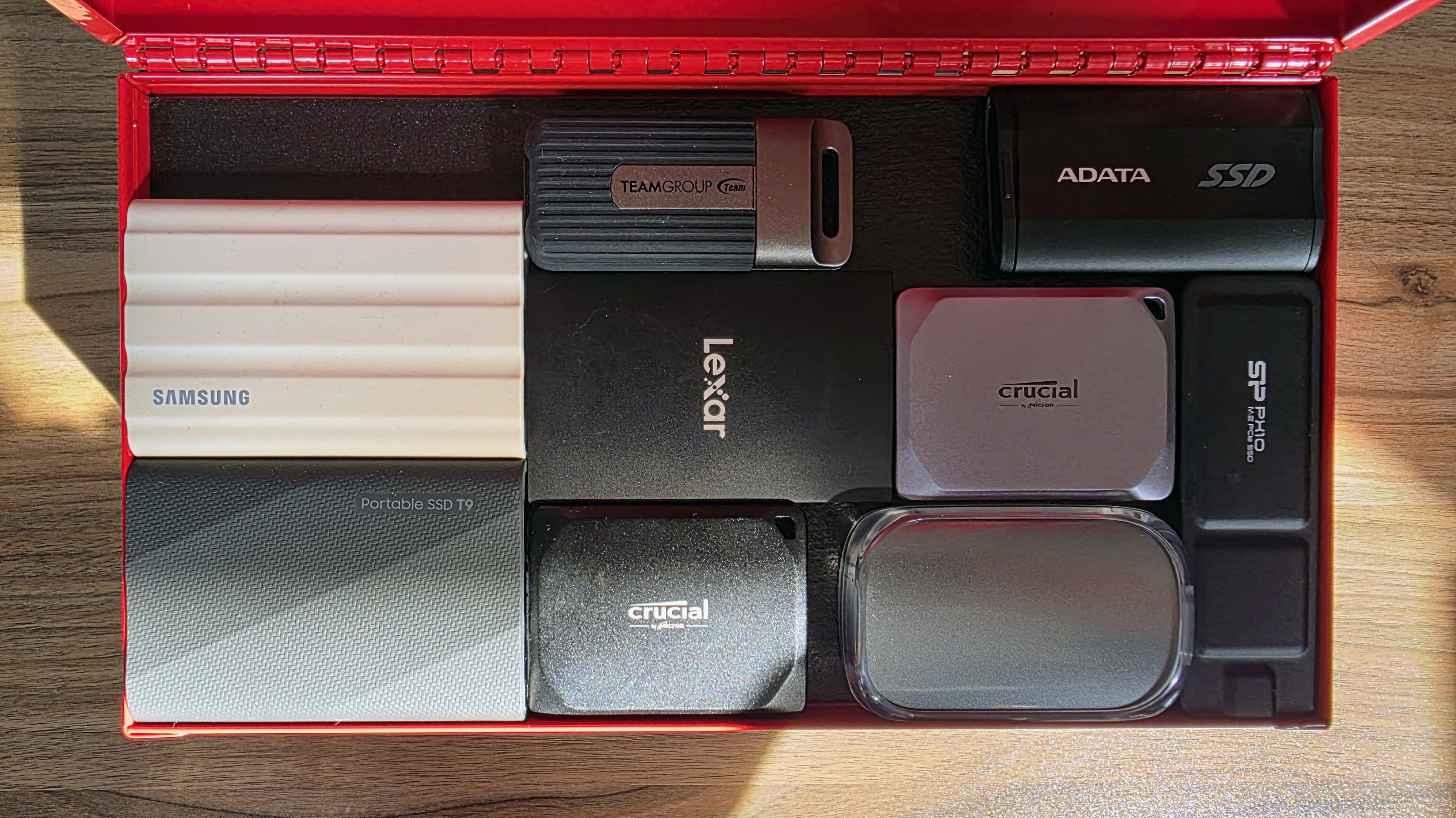 A collection of the best SSDs we've tested, in a small red toolbox, on a wooden table