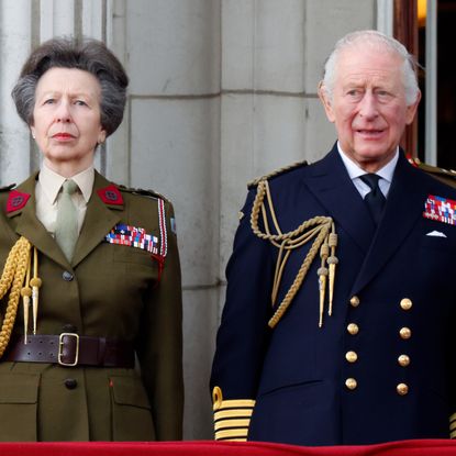 Princess Anne wears an olive green military uniform and stands with brother King Charles, who wears a navy naval uniform