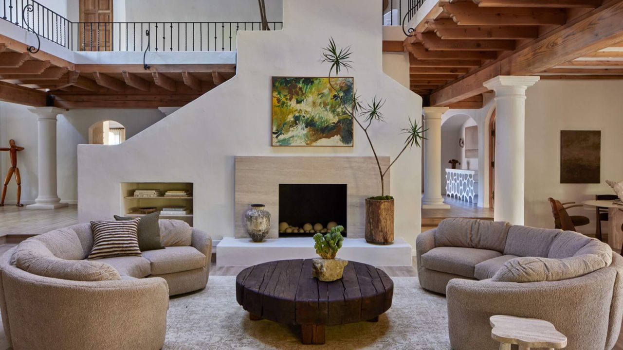 Living room with beige curved sofas, dark wood coffee table and off-white limewash walls