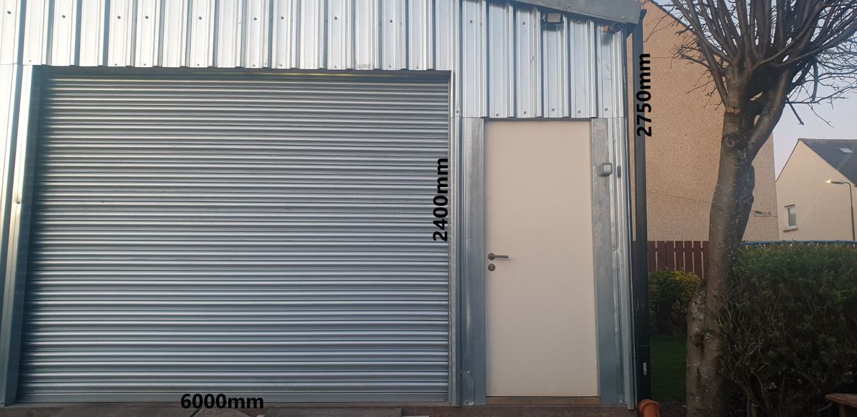 A large garage with metal cladding metal shutter in a garden