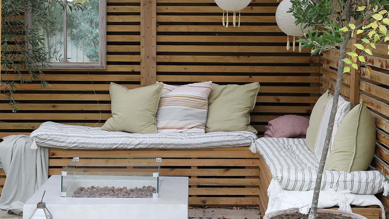 Garden pergola with seating area decorated with cushions.