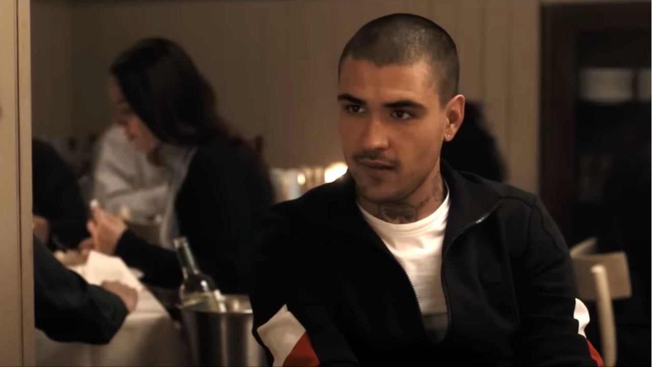 Andrea Dodero siede in un ristorante e dà uno sguardo interrogativo in The Equalizer 3.