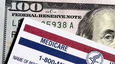 The top corner of a Medicare card sitting on top of a hundred-dollar bill.