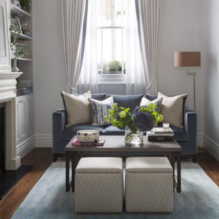 Renovated sitting room. A sofa with cushions, modern floor lamp, wooden floor and fireplace. Mixture of cool colours and rich textures. London terraced home to Irina and David Nedashkovskaya