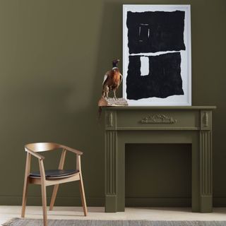 A dark olive green wall and a fireplace