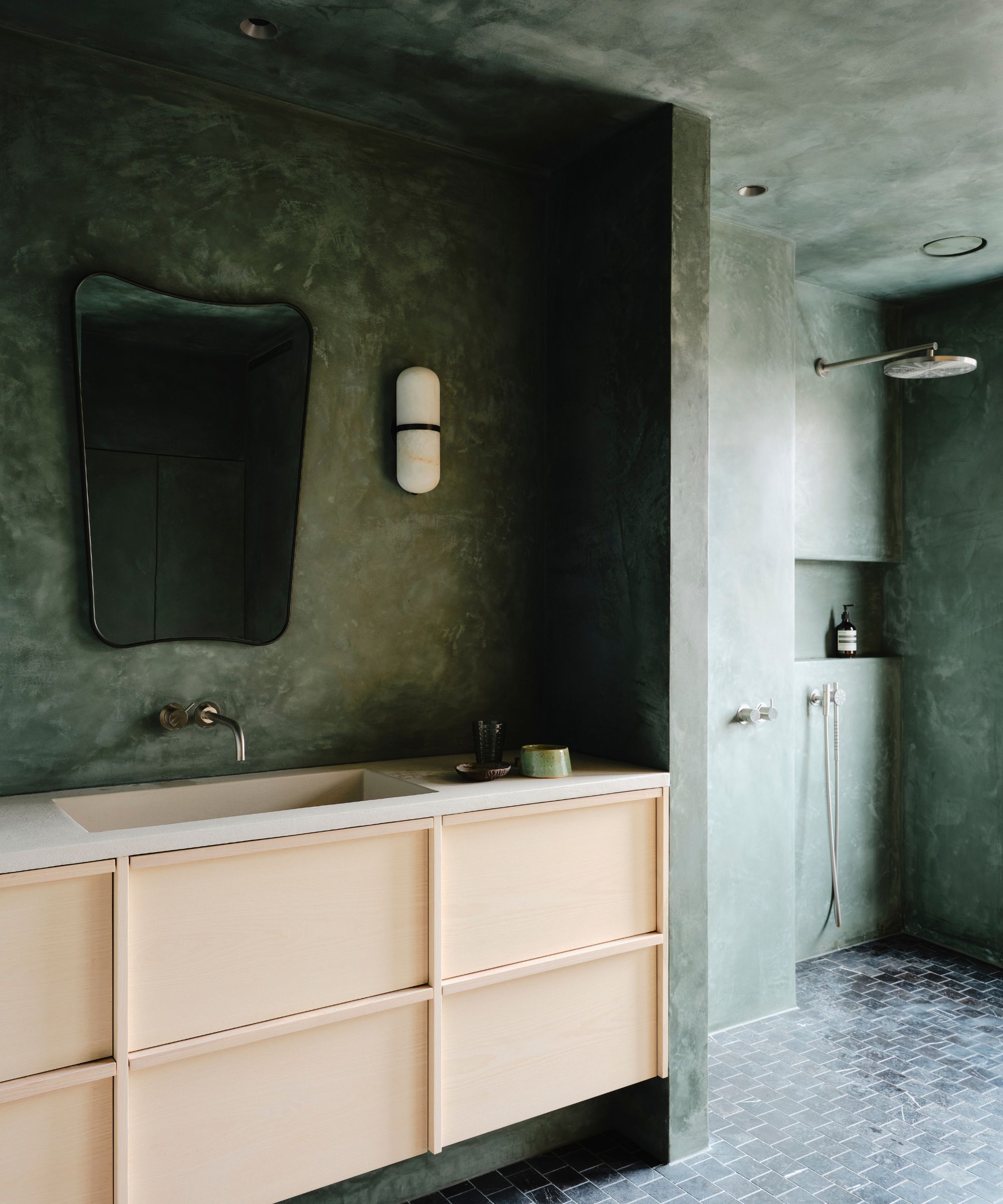 Green bathroom with textured plaster walls and pale wooden vanity