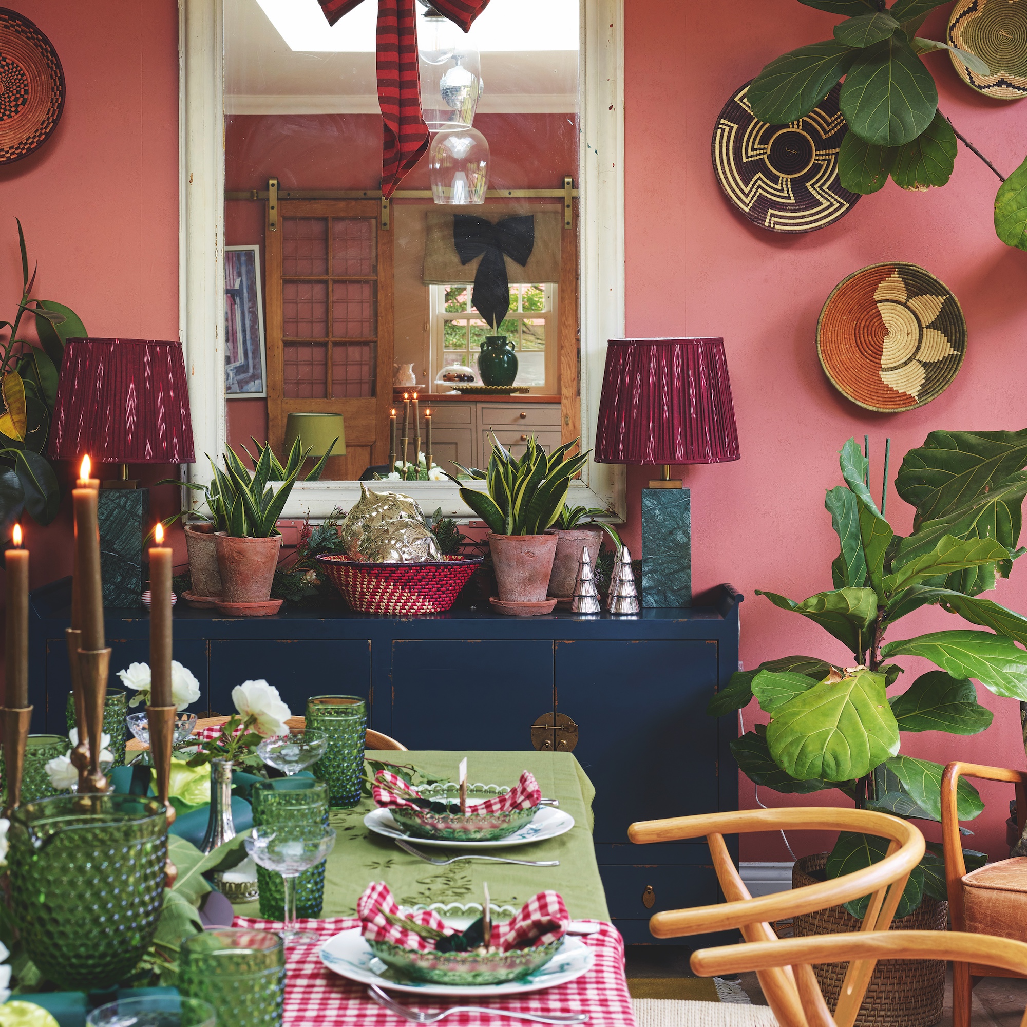 dining table set for christmas with red check cloth and green runner with candles