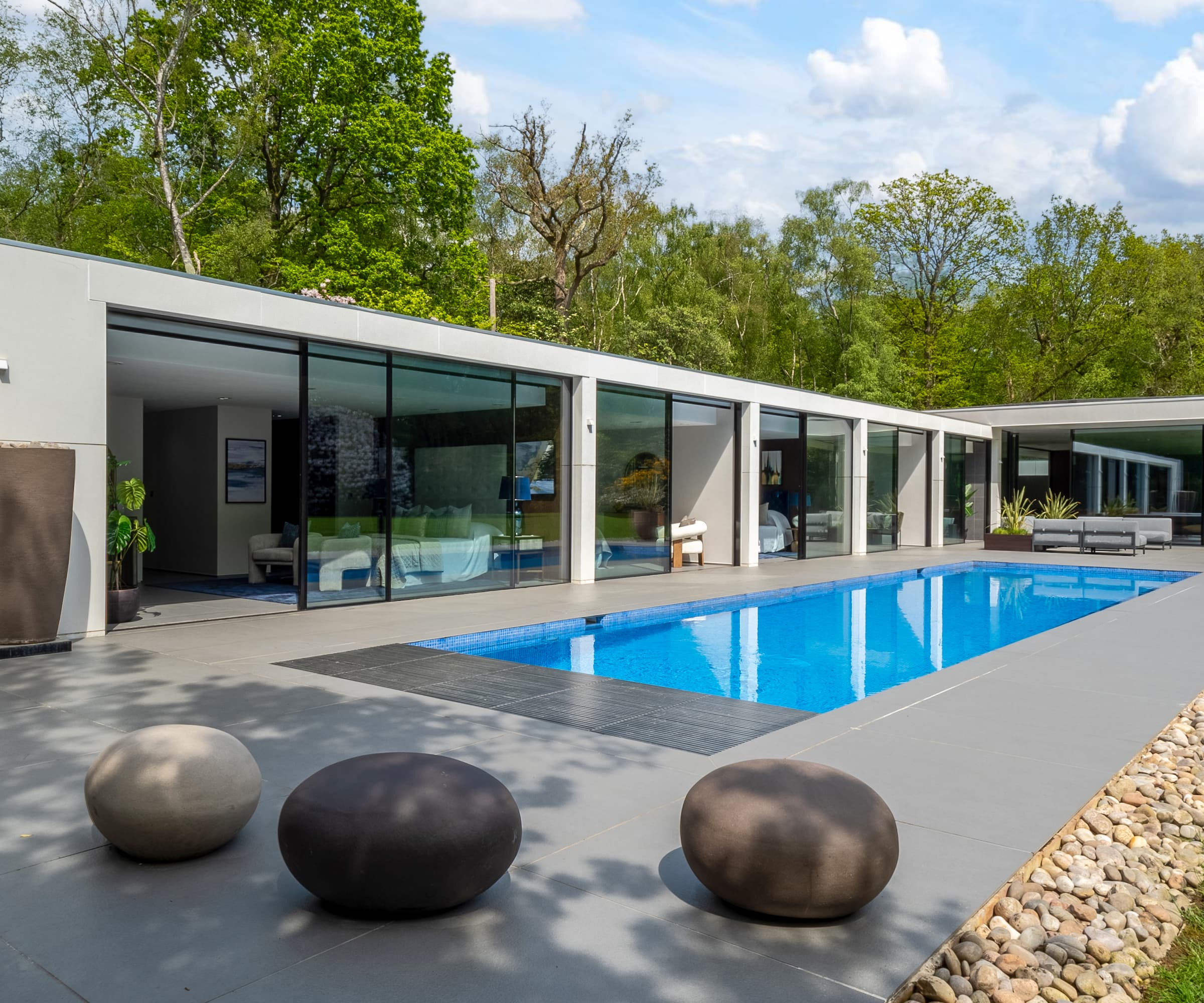 A swimming pool outside of four bedrooms with ceiling to glass windows