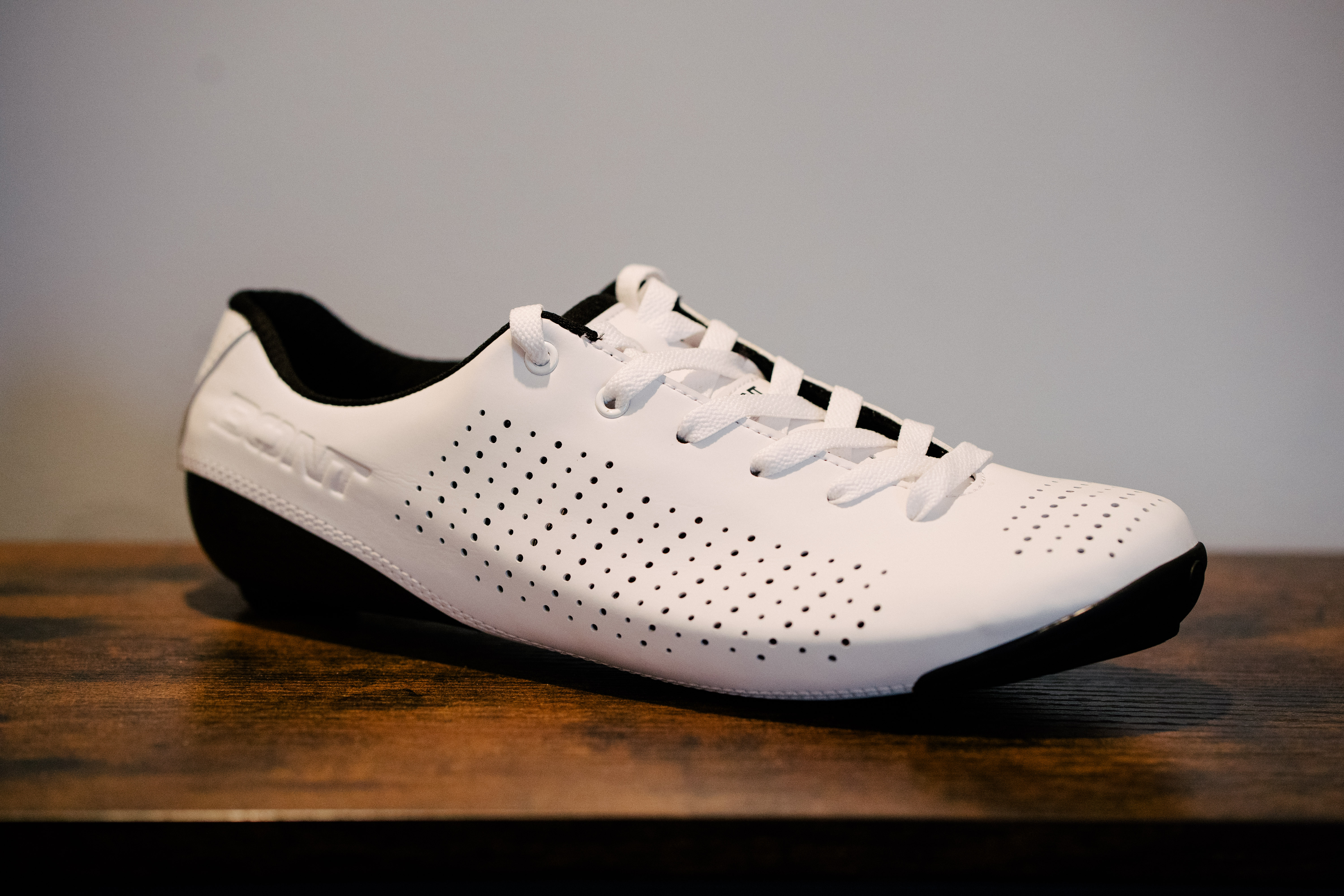 A lace up set of bike shoes on a wooden shelf