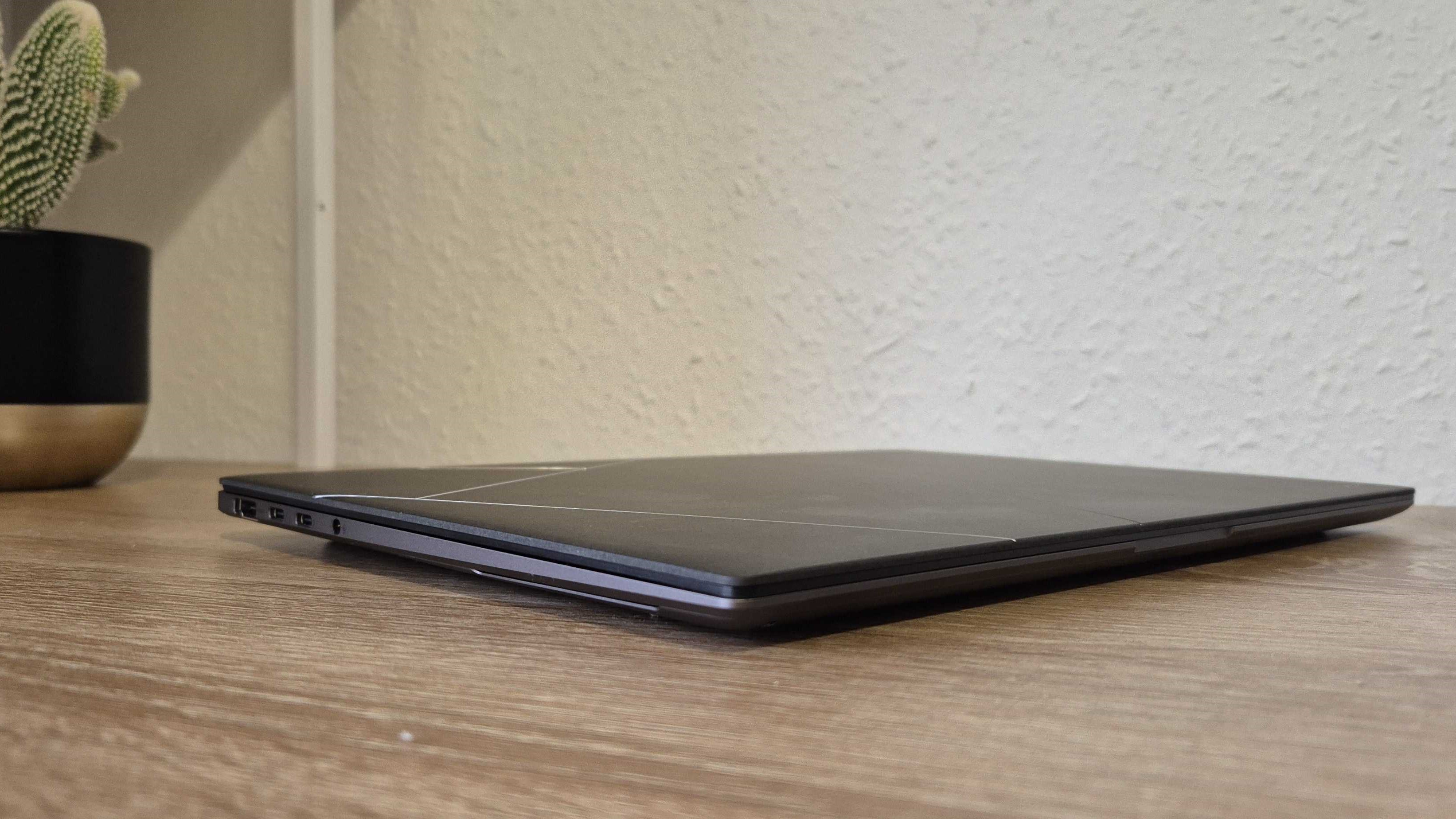 The Asus Zenbook S 14 with its lid closed on a desk next to a cactus