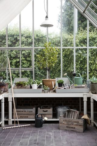 interior of a traditonal greenhouse with a potting table and shelves
