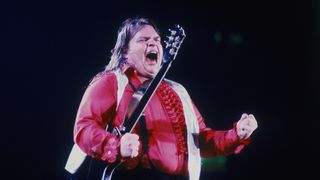 American rock singer Meat Loaf performing on stage and holding a guitar, circa 1977