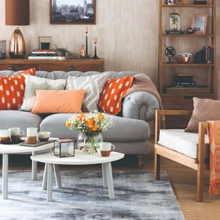 A living room with a grey sofa with contrasting cushions and a white and grey set of nesting coffee tables in front