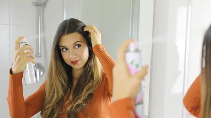 woman spraying dry shampoo on hair