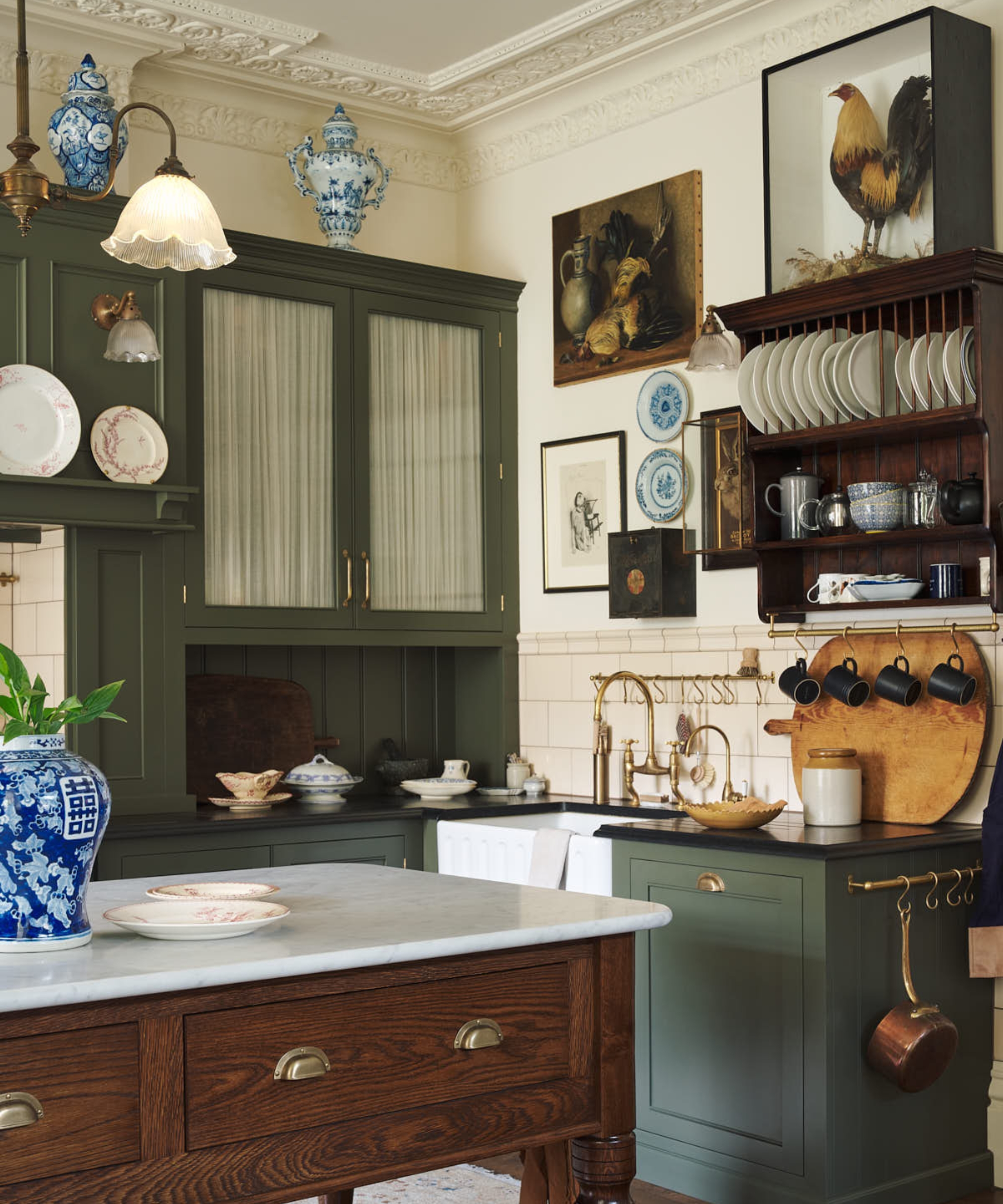 A green and white kitchen with a freestanding wooden island and a mismatched collection of art on the walls