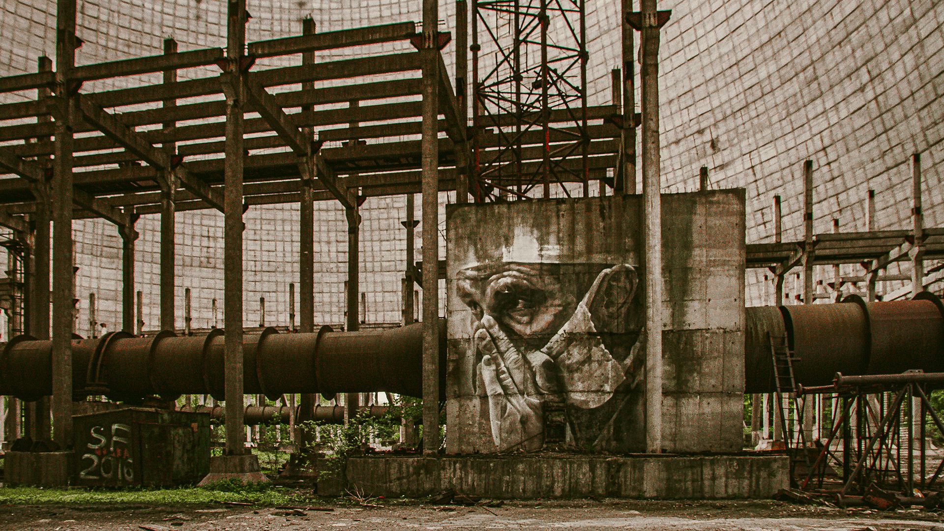 A view of a nuclear power plant with a mural of a person wearing a gas mask painted on a tower.