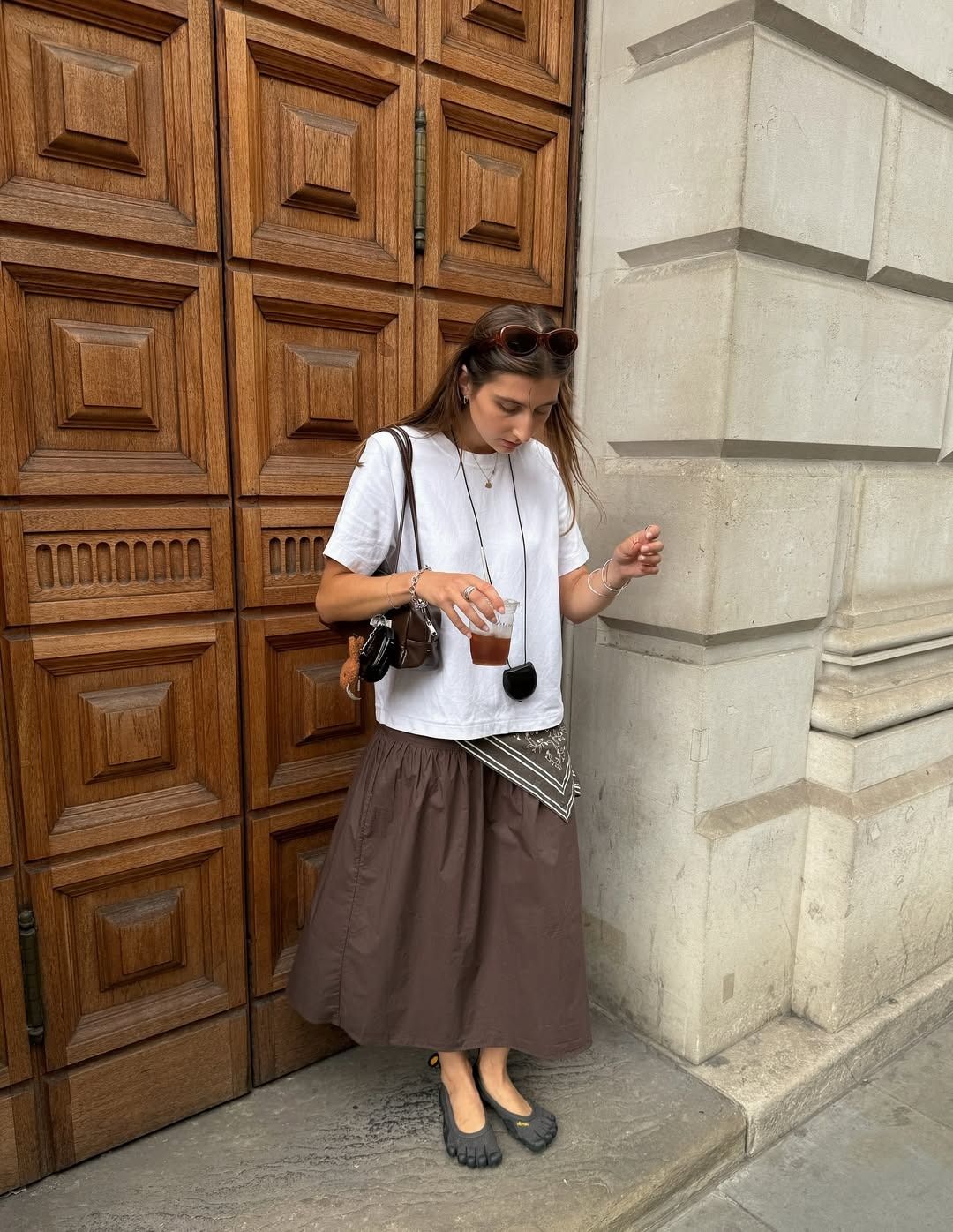Influencer poppy wears a brown skirt with a oversized white crewneck t-shirt.