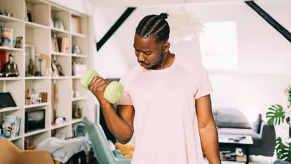 Man doing dumbbell curls at home.