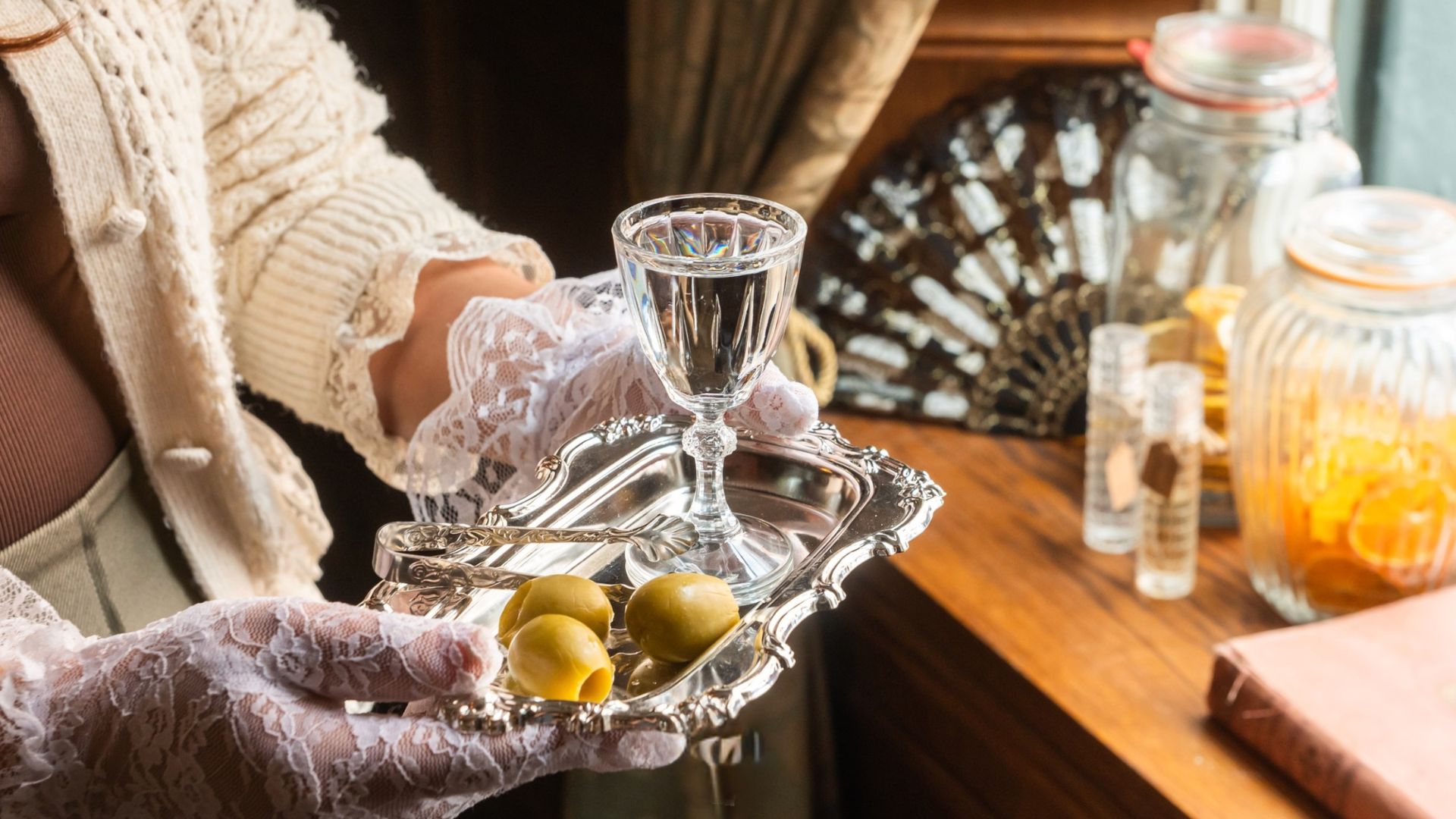 an image of a server with a silver tray with a martini glass and some olives on it