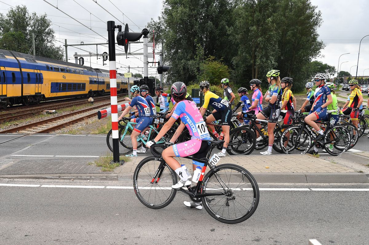 The riders wait for a train to pass