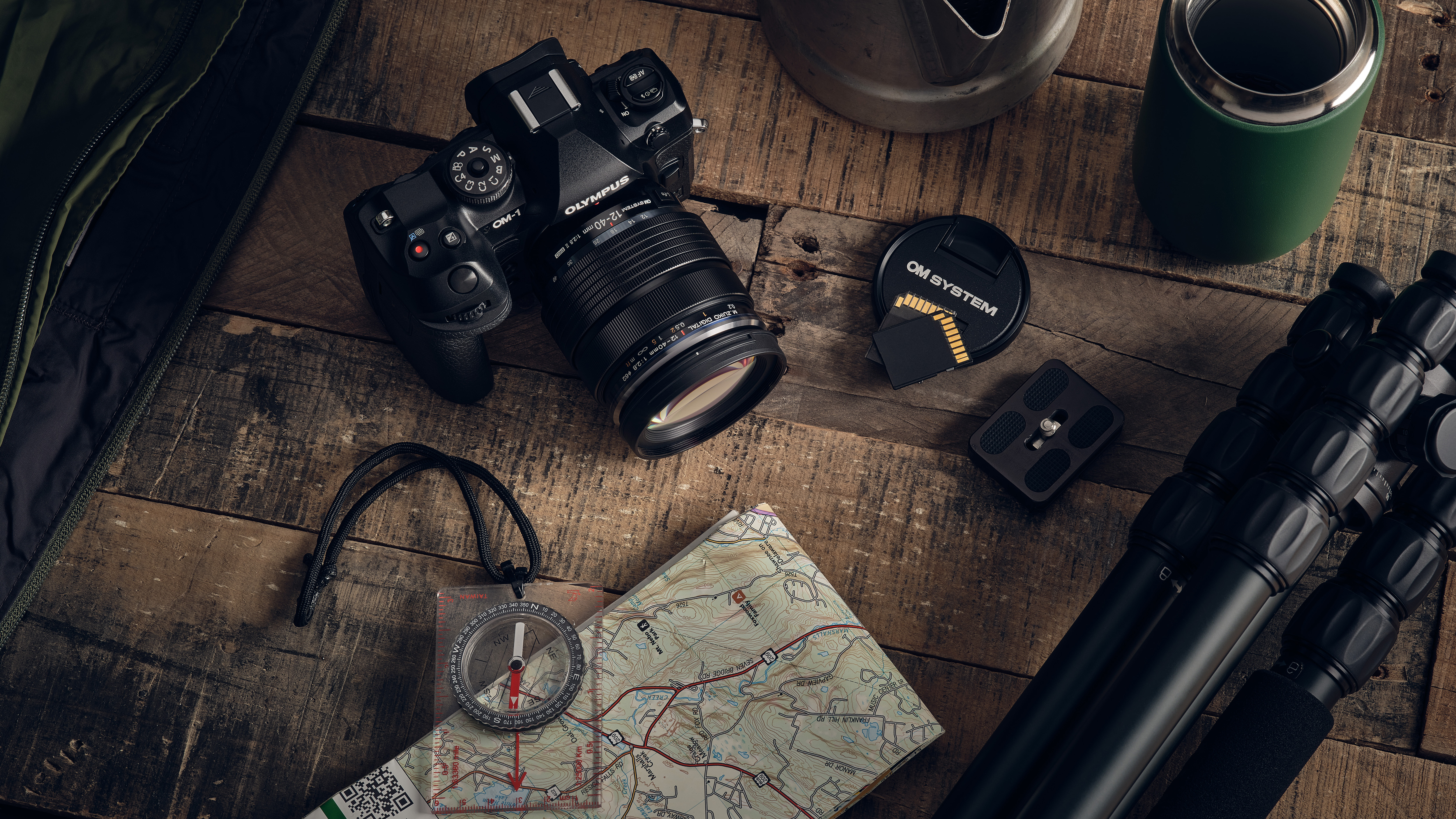 A camera on a table next to a compass and tripod