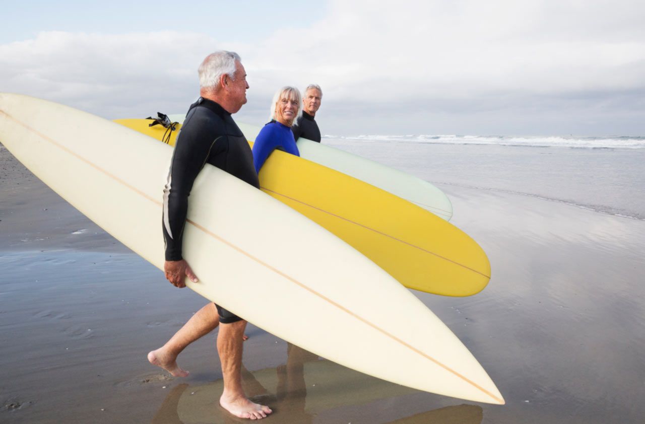 Three men walk toward the water with surfboards.