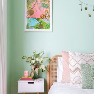 Green bedroom with pink bedding and white bedside table