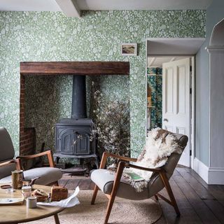 A classic living room with emerald green Atacama wallpaper wallcovering by Farrow & Ball with black stove fireplace in wall recess