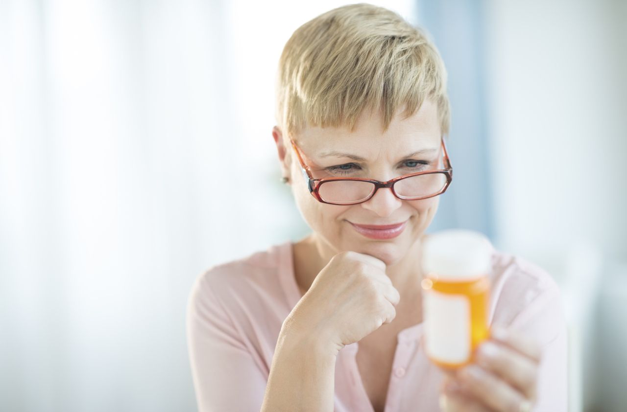 Woman Reading Label On Pill Bottle