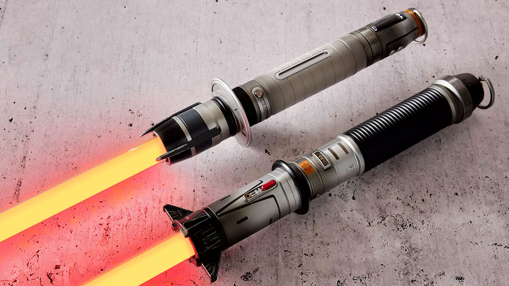 Two metal lightsabers with red glowing blades are displayed on a marbel surface.