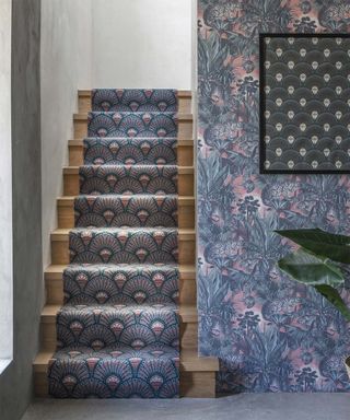 Art Deco inspired stair runner with fan shaped motif in blue and pink alongside jungle-inspired hallway wallpaper idea and framed wall decor
